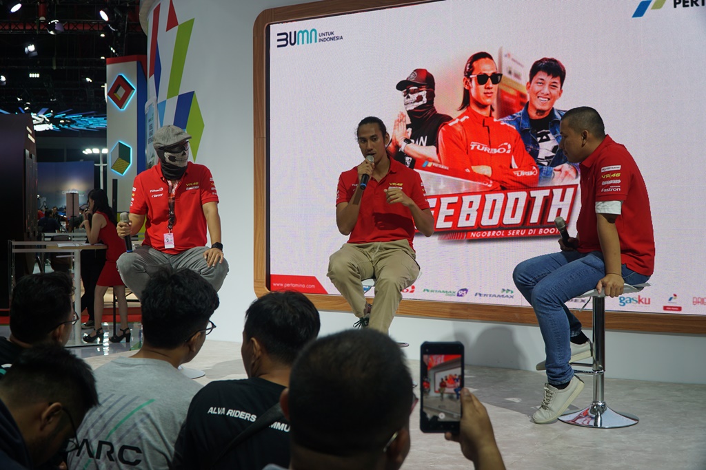 Sean Gelael berbincang dengan Youtuber Motomobi dan Ridwan Hanif di booth Pertamina pada IIMS 2024 